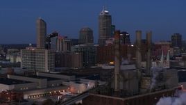5.7K aerial stock footage approach city skyline at twilight from smoke stacks, Downtown Indianapolis, Indiana Aerial Stock Footage | DX0001_002964