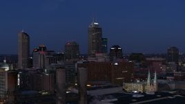 5.7K aerial stock footage reverse view of giant skyscrapers of the city skyline at twilight, seen from smoke stacks, Downtown Indianapolis, Indiana Aerial Stock Footage | DX0001_002972