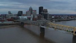 5.7K aerial stock footage ascend by bridge spanning river at sunset for view of skyline, Downtown Louisville, Kentucky Aerial Stock Footage | DX0001_003074