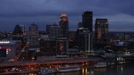5.7K aerial stock footage of flying by the skyline lit up at twilight, seen during ascent from Ohio River, Downtown Louisville, Kentucky Aerial Stock Footage | DX0001_003098