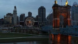 5.7K aerial stock footage pass Roebling Bridge to approach Ferris wheel and city skyline at sunset, Downtown Cincinnati, Ohio Aerial Stock Footage | DX0001_003157