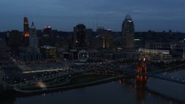 5.7K aerial stock footage of the city skyline and bridge lit for twilight, seen from Ohio River, Downtown Cincinnati, Ohio Aerial Stock Footage | DX0001_003164
