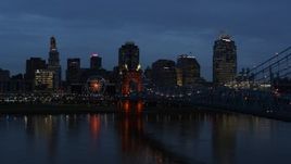 5.7K aerial stock footage reverse view of city skyline and Roebling Bridge lit up at twilight, seen from Ohio River, Downtown Cincinnati, Ohio Aerial Stock Footage | DX0001_003170