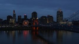 5.7K aerial stock footage of city skyline behind Roebling Bridge lit up at twilight, seen from Ohio River, Downtown Cincinnati, Ohio Aerial Stock Footage | DX0001_003171