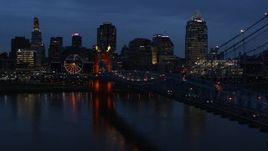 5.7K aerial stock footage follow Roebling Bridge lit up at twilight, approach city skyline, Downtown Cincinnati, Ohio Aerial Stock Footage | DX0001_003175