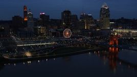 5.7K aerial stock footage flying by lights of city skyline and bridge at twilight, seen from across river, Downtown Cincinnati, Ohio Aerial Stock Footage | DX0001_003179