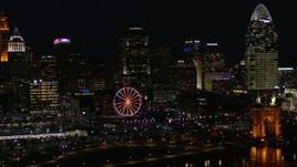 5.7K aerial stock footage flying by the city skyline and Ferris wheel at night near Roebling Bridge, Downtown Cincinnati, Ohio Aerial Stock Footage | DX0001_003198