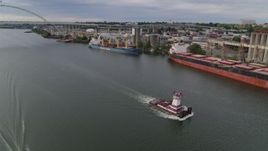 5.7K aerial stock footage tracking a tugboat sailing past cargo ships and North Portland, Oregon Aerial Stock Footage | DX0001_013_008