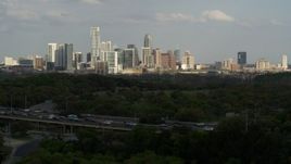 5.7K aerial stock footage ascend from green trees by freeway for wide view of city's towering skyline, Downtown Austin, Texas Aerial Stock Footage | DX0002_104_023