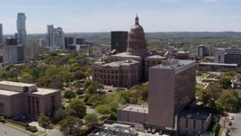 5.7K aerial stock footage of fly away from the Texas State Capitol, descend near government office building in Downtown Austin, Texas Aerial Stock Footage | DX0002_107_023