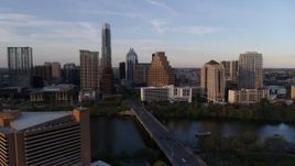 5.7K aerial stock footage of flying away from skyline across bridge and Lady Bird Lake at sunset in Downtown Austin, Texas Aerial Stock Footage | DX0002_110_012