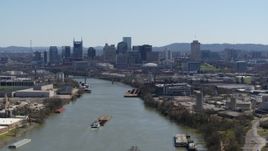 5.7K aerial stock footage flying by barge sailing the river toward the city's skyline, Downtown Nashville, Tennessee Aerial Stock Footage | DX0002_112_022
