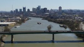 5.7K aerial stock footage a barge on the river, sailing toward the city's skyline, seen seen while flying by bridge, Downtown Nashville, Tennessee Aerial Stock Footage | DX0002_112_026