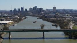5.7K aerial stock footage passing a bridge with view of barge sailing toward the city's skyline, Downtown Nashville, Tennessee Aerial Stock Footage | DX0002_112_028