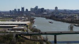 5.7K aerial stock footage a highway bridge, with view of barge sailing toward city's skyline, Downtown Nashville, Tennessee Aerial Stock Footage | DX0002_112_029