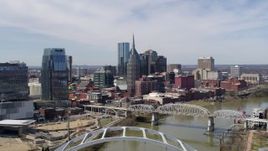 5.7K aerial stock footage fly away from and past skyscrapers, and bridge spanning the river in Downtown Nashville, Tennessee Aerial Stock Footage | DX0002_116_002