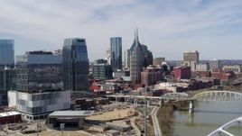 5.7K aerial stock footage flying past skyscrapers near a bridge spanning the river in Downtown Nashville, Tennessee Aerial Stock Footage | DX0002_116_003