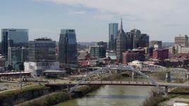 5.7K aerial stock footage of slowly flying by the river and bridge, focus on skyscrapers in Downtown Nashville, Tennessee Aerial Stock Footage | DX0002_116_025
