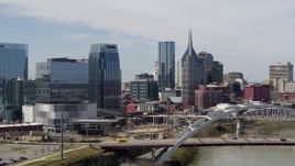 5.7K aerial stock footage flyby the river and bridge, approach office building and skyscrapers in Downtown Nashville, Tennessee Aerial Stock Footage | DX0002_116_027