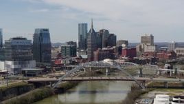 5.7K aerial stock footage pass a bridge and the river while focused on city skyscrapers in Downtown Nashville, Tennessee Aerial Stock Footage | DX0002_116_039