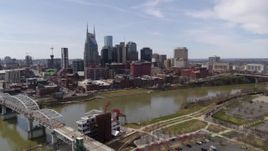 5.7K aerial stock footage reverse view of the city's riverfront skyscrapers, descend near pedestrian bridge, Downtown Nashville, Tennessee Aerial Stock Footage | DX0002_117_004