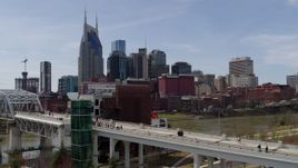 5.7K aerial stock footage descend by pedestrian bridge with view of city's skyline, Downtown Nashville, Tennessee Aerial Stock Footage | DX0002_117_025