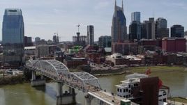 5.7K aerial stock footage descend near pedestrian bridge with view of Broadway across the Cumberland River, Downtown Nashville, Tennessee Aerial Stock Footage | DX0002_117_033