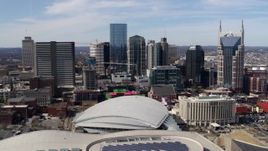 5.7K aerial stock footage of flying by the city's skyline behind the arena, Downtown Nashville, Tennessee Aerial Stock Footage | DX0002_117_034