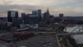 5.7K aerial stock footage of flying away from city skyscrapers beside the river at sunset, Downtown Nashville, Tennessee Aerial Stock Footage | DX0002_119_037