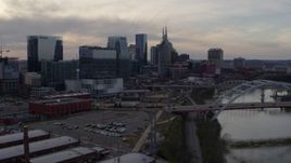 5.7K aerial stock footage ascend past bridges and Cumberland River at sunset for view of skyscrapers, Downtown Nashville, Tennessee Aerial Stock Footage | DX0002_119_040