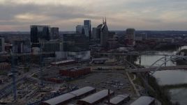 5.7K aerial stock footage reverse view of skyline before passing bridge and Cumberland River at sunset, Downtown Nashville, Tennessee Aerial Stock Footage | DX0002_119_041