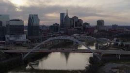 5.7K aerial stock footage flying by the city skyline near bridges and Cumberland River at sunset, Downtown Nashville, Tennessee Aerial Stock Footage | DX0002_119_043