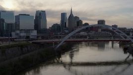 5.7K aerial stock footage fly close to bridge on Cumberland River at sunset, skyline in background, Downtown Nashville, Tennessee Aerial Stock Footage | DX0002_119_044