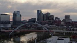 5.7K aerial stock footage city skyline seen while flying by bridge on Cumberland River at sunset, Downtown Nashville, Tennessee Aerial Stock Footage | DX0002_120_002