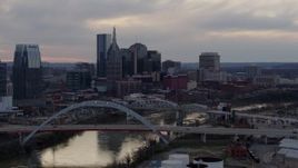 5.7K aerial stock footage flying away from riverfront skyline, bridges, and the Cumberland River at sunset, Downtown Nashville, Tennessee Aerial Stock Footage | DX0002_120_007
