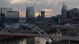 5.7K aerial stock footage focus on a tall skyscraper while passing a bridge on the river at sunset, Downtown Nashville, Tennessee Aerial Stock Footage | DX0002_120_014