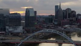 5.7K aerial stock footage focus on a tall skyscraper while flying by a bridge on the river at sunset, Downtown Nashville, Tennessee Aerial Stock Footage | DX0002_120_015