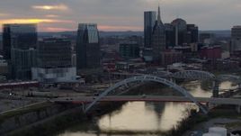 5.7K aerial stock footage reverse view of skyline and bridge on the river at sunset, Downtown Nashville, Tennessee Aerial Stock Footage | DX0002_120_016