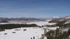 5.7K aerial stock footage of flying by country road in snowy valley with view of mountains, New Mexico Aerial Stock Footage | DX0002_134_017