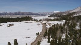 5.7K aerial stock footage pass and follow a country road in snowy valley with view of mountains, New Mexico Aerial Stock Footage | DX0002_134_018