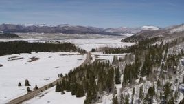 5.7K aerial stock footage fly away from and near a country road in snowy valley with view of mountains, New Mexico Aerial Stock Footage | DX0002_134_020