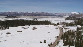 5.7K aerial stock footage of flying by a deserted country road in snowy valley with view of mountains, New Mexico Aerial Stock Footage | DX0002_134_021