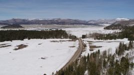 5.7K aerial stock footage of a lonely country road in snowy valley with view of distant mountains, New Mexico Aerial Stock Footage | DX0002_134_023