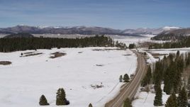 5.7K aerial stock footage pass a lonely country road in snowy valley with view of distant mountains, New Mexico Aerial Stock Footage | DX0002_134_024