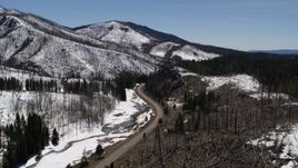5.7K aerial stock footage of following a winding road between snowy mountains and evergreens, New Mexico Aerial Stock Footage | DX0002_134_030