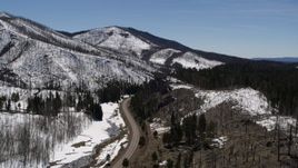 5.7K aerial stock footage reverse view of black car on winding road between snowy mountains and evergreens, New Mexico Aerial Stock Footage | DX0002_134_031