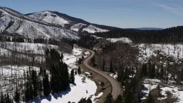 5.7K aerial stock footage reverse view of winding road by snowy mountains and trees, New Mexico Aerial Stock Footage | DX0002_134_032
