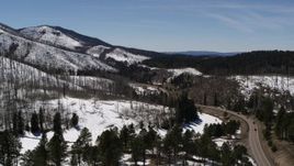 5.7K aerial stock footage passing winding road and four black cars by snowy mountains, New Mexico Aerial Stock Footage | DX0002_134_034