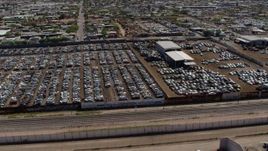 5.7K aerial stock footage orbit and fly away from rows of cars at an automobile junkyard in Phoenix, Arizona Aerial Stock Footage | DX0002_137_009