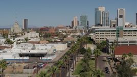 5.7K aerial stock footage reverse view of palm trees at city park and tall office buildings in Downtown Phoenix, Arizona Aerial Stock Footage | DX0002_137_037